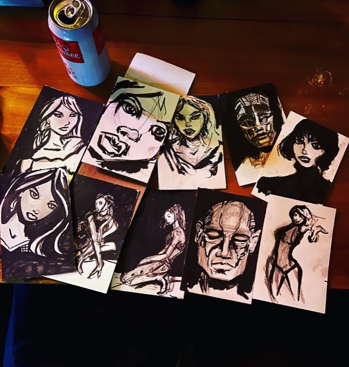 Desk with pens, pencils and a stack of finished sketches